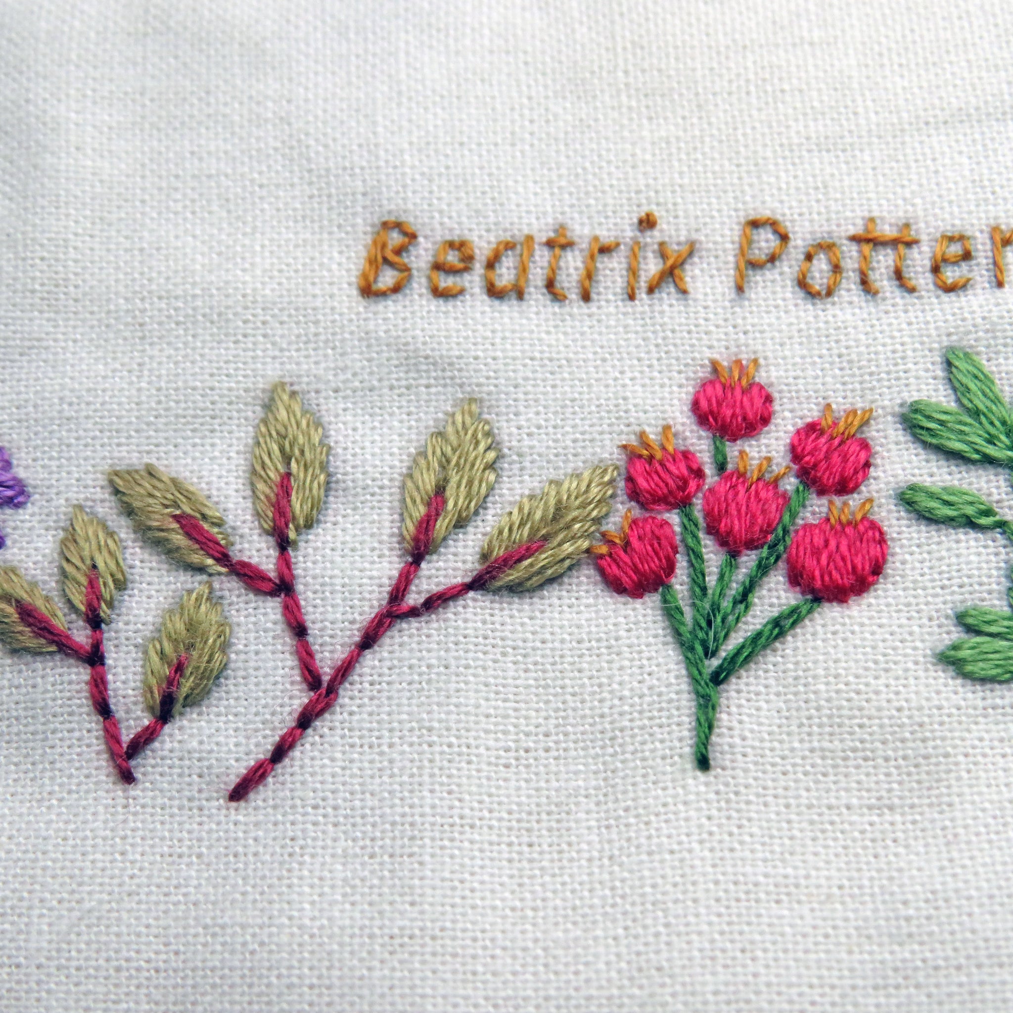 Embroidered floral design with leaves and flowers on a white fabric background