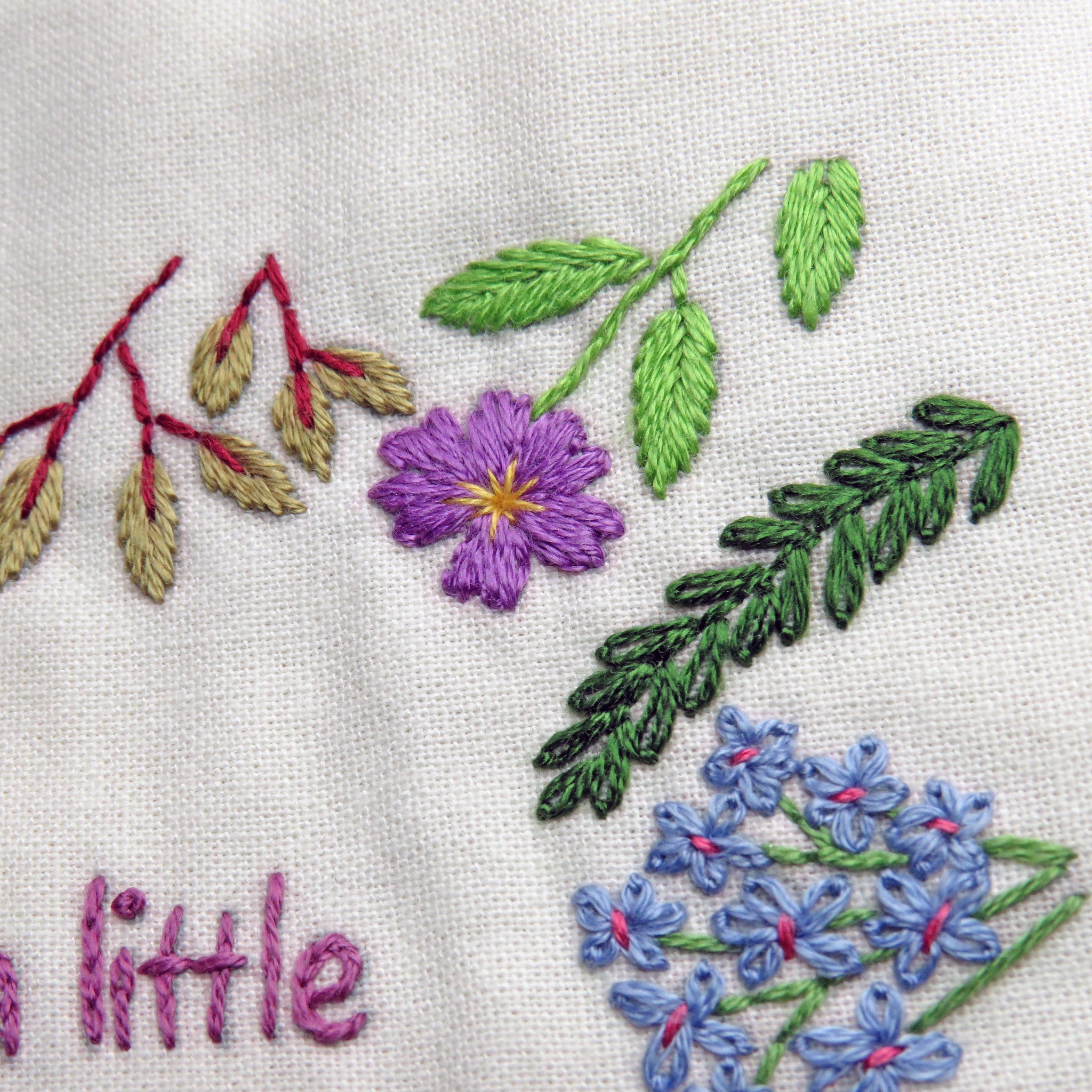Embroidered floral design with leaves and flowers on a white fabric background