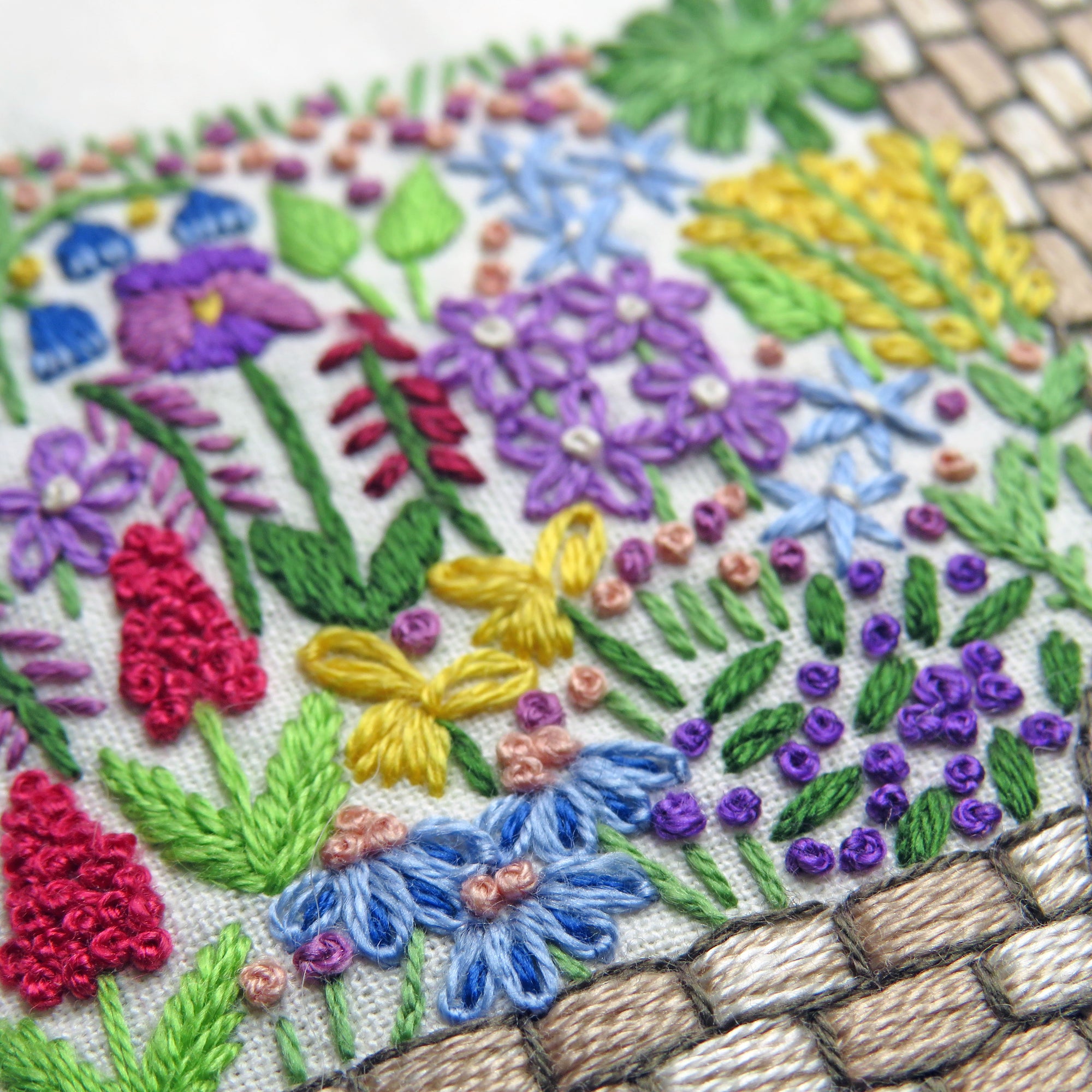 Embroidered design of colorful flowers and plants on fabric.