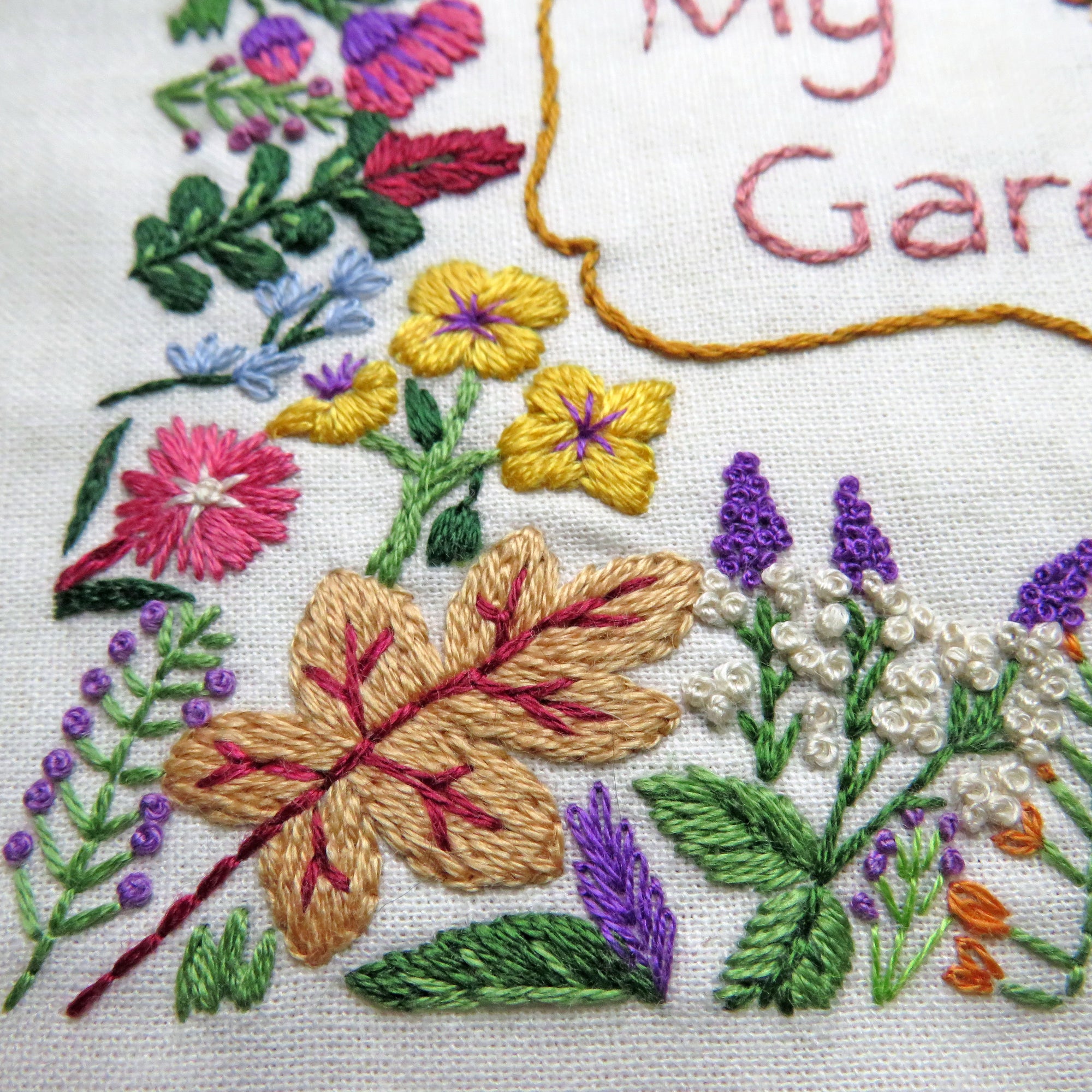 Embroidered floral design with leaves and text on a white background