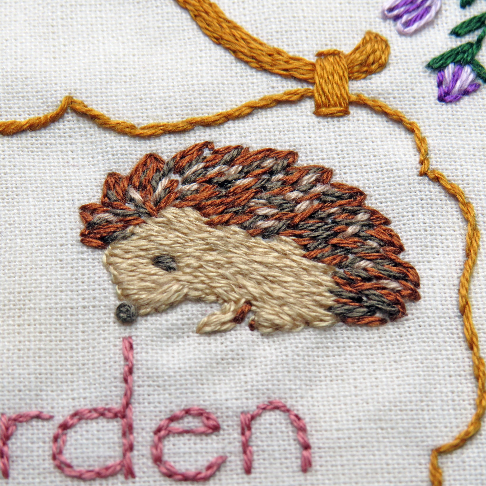 Embroidered hedgehog design on fabric with 'arden' text