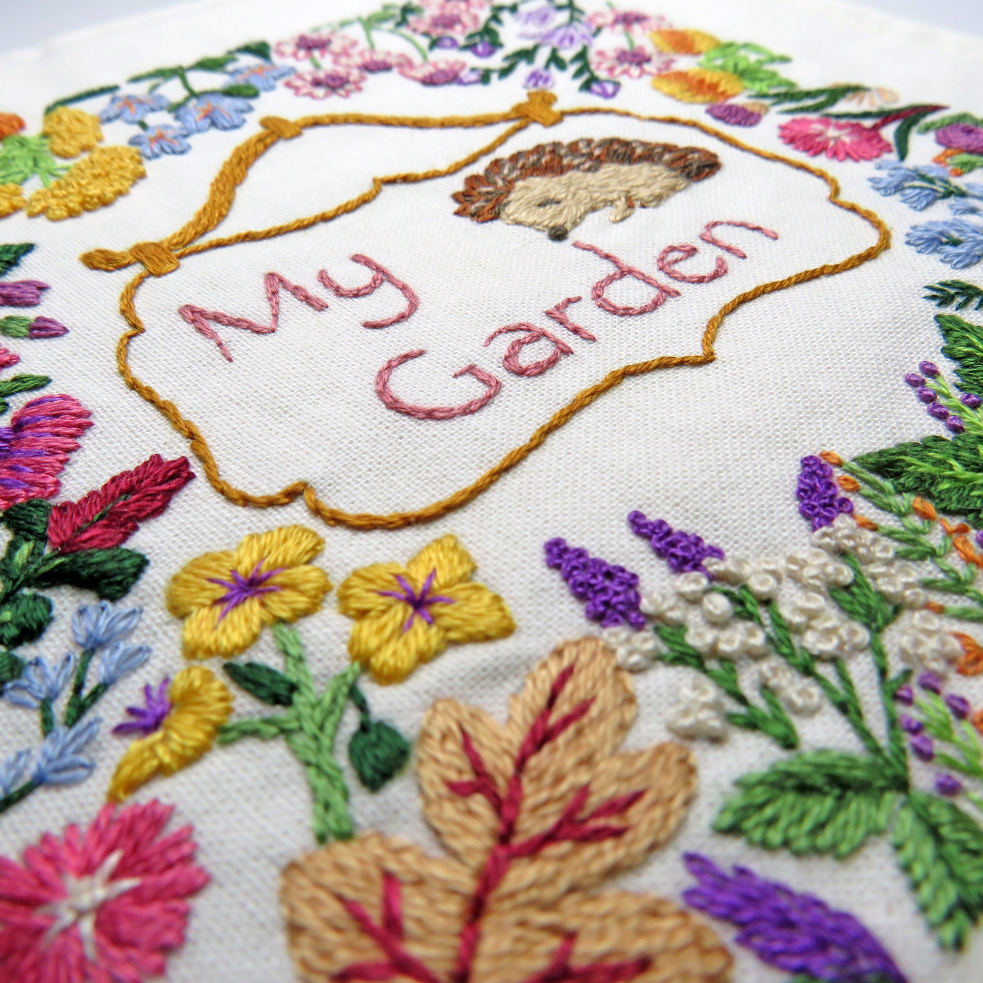 Embroidered design with flowers and 'My Garden' text on fabric