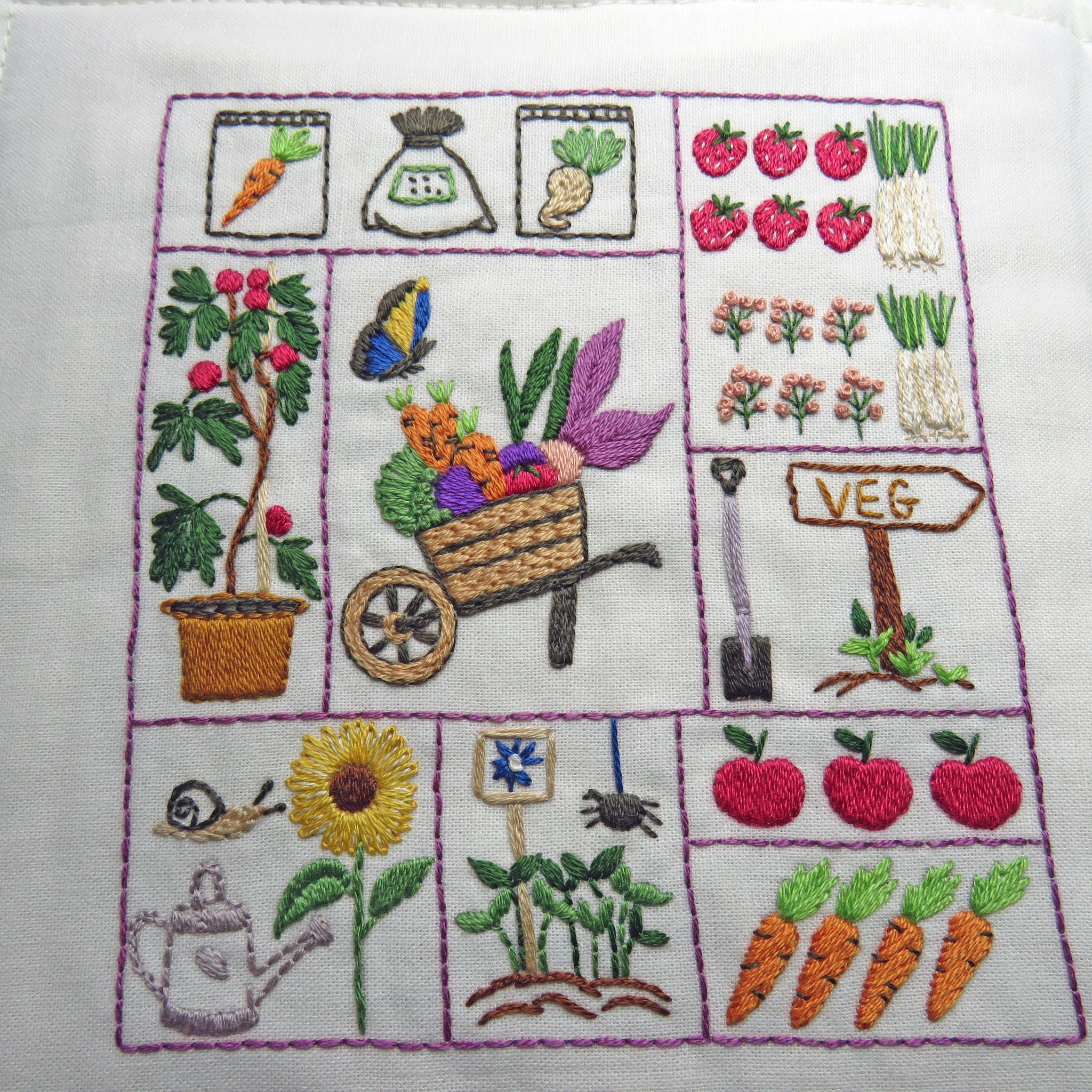 Embroidered panel with gardening-themed designs on a white background