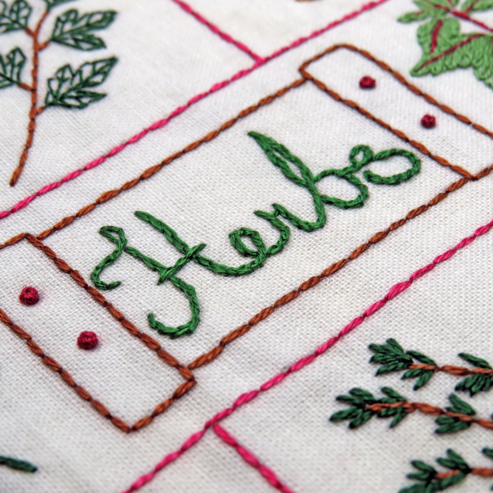 Embroidered text with green thread on a white fabric background
