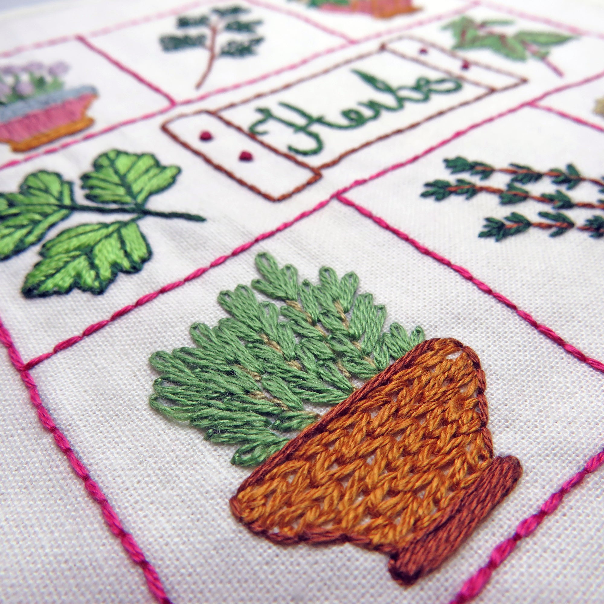 Embroidered design of a carrot and leaves on a white fabric background