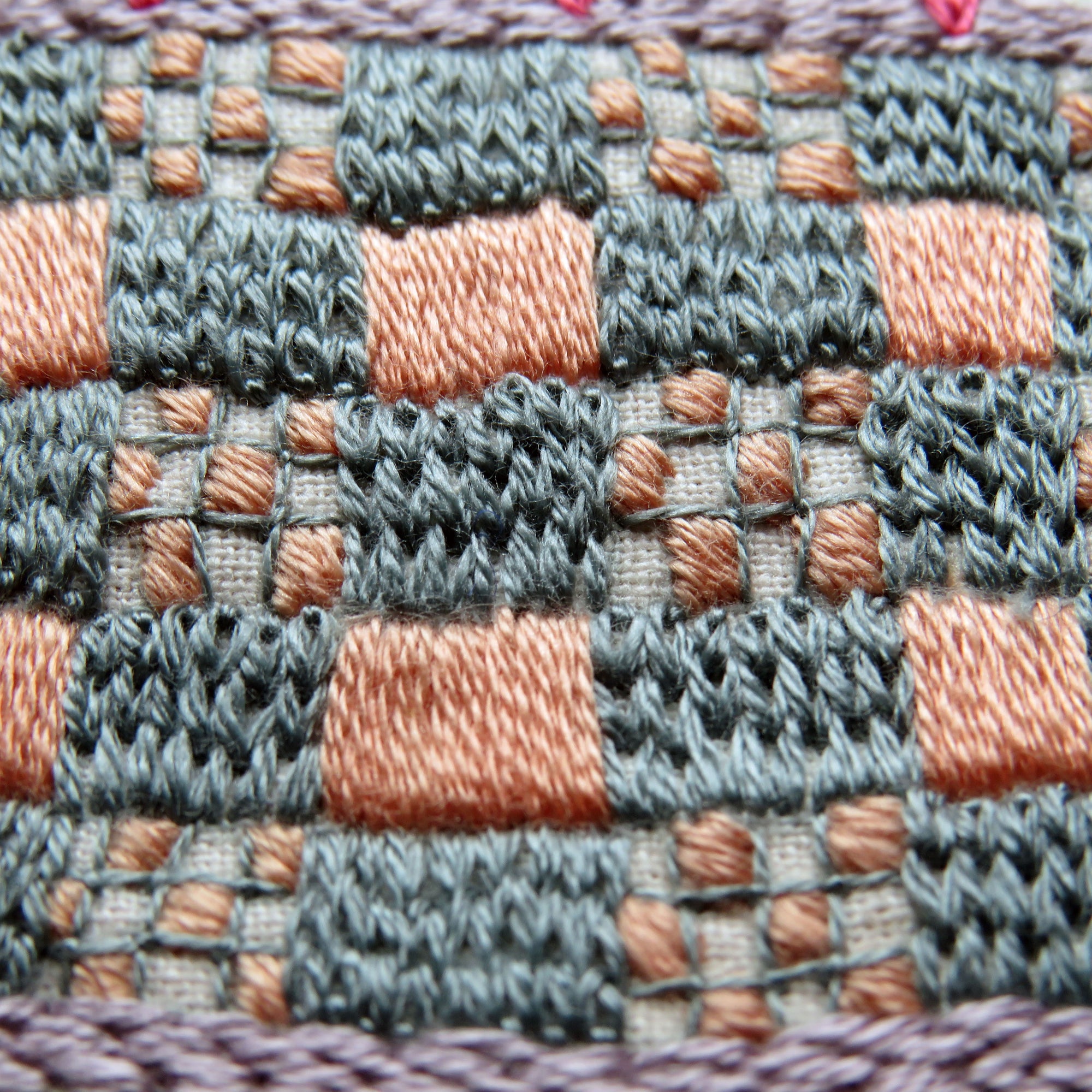 Close-up of a woven fabric with a checkered pattern in shades of gray, pink, and purple.