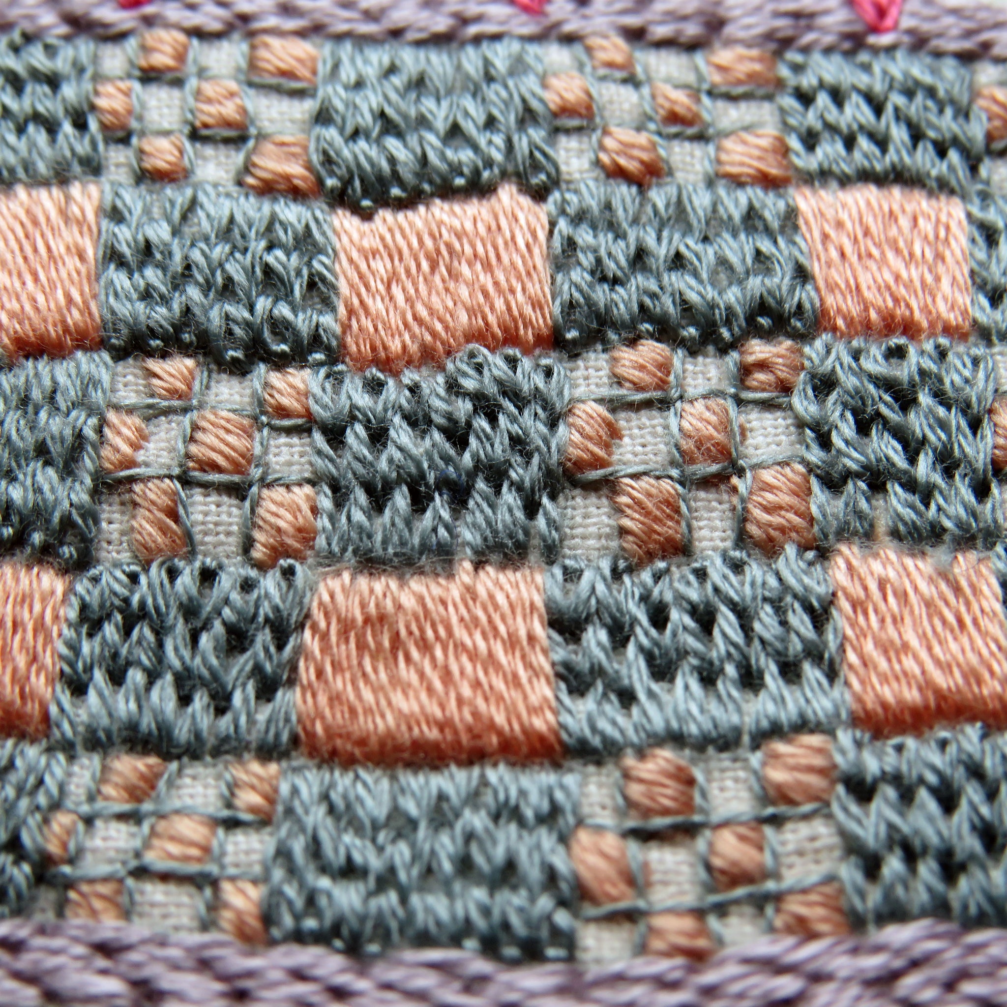 Close-up of a woven fabric with a checkered pattern in shades of gray, pink, and purple.