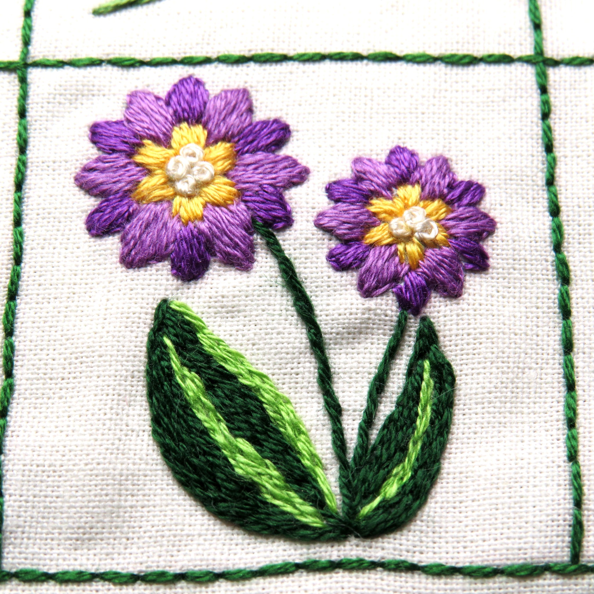 Embroidered flowers on fabric with green grid lines