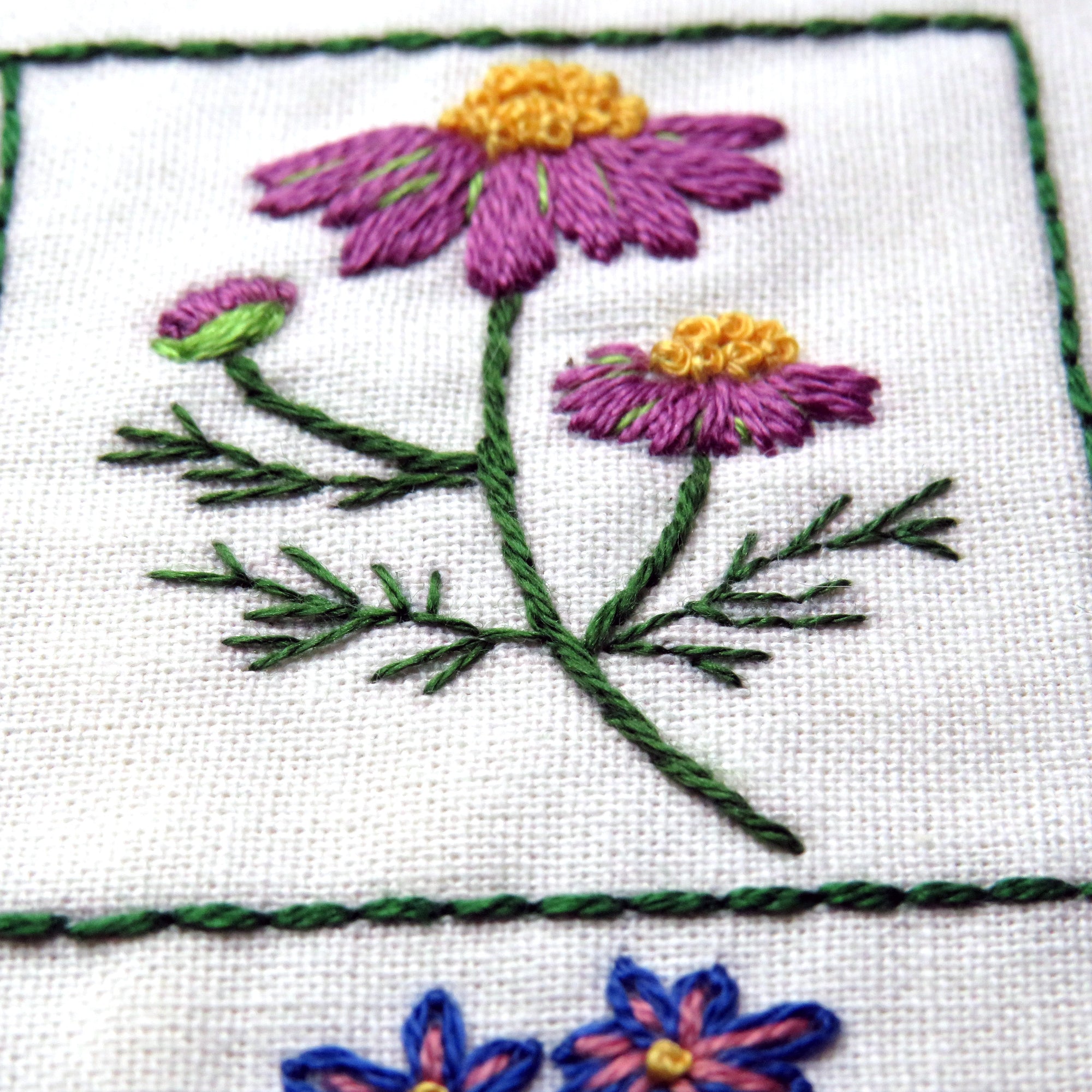 Embroidered flowers on fabric with green thread