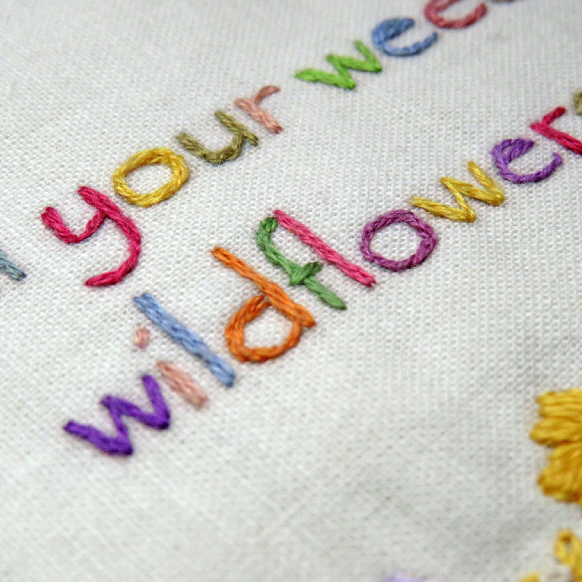 Embroidery with colorful text 'Your Wildflower' on a white fabric background