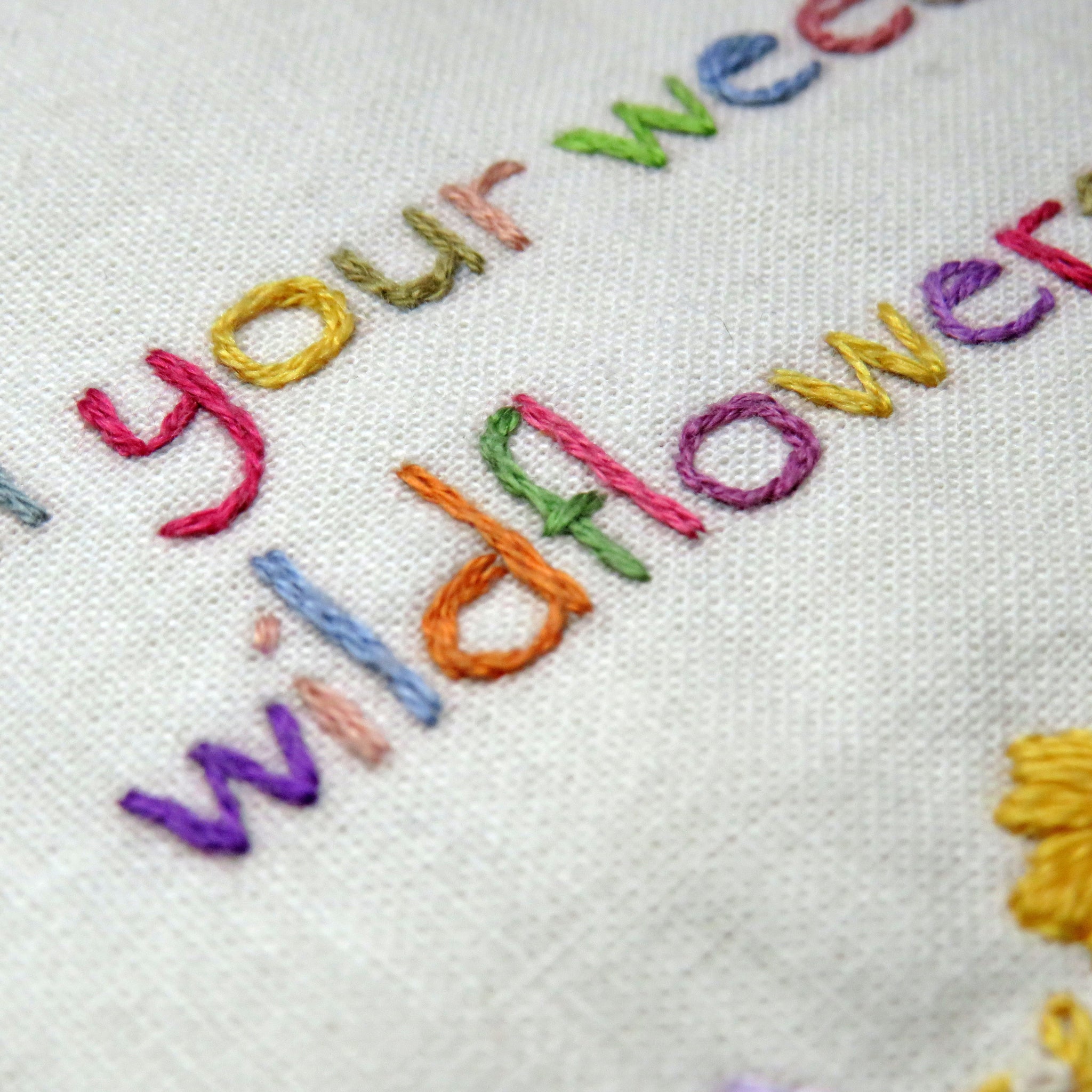 Embroidery with colorful text 'Your Wildflower' on a white fabric background