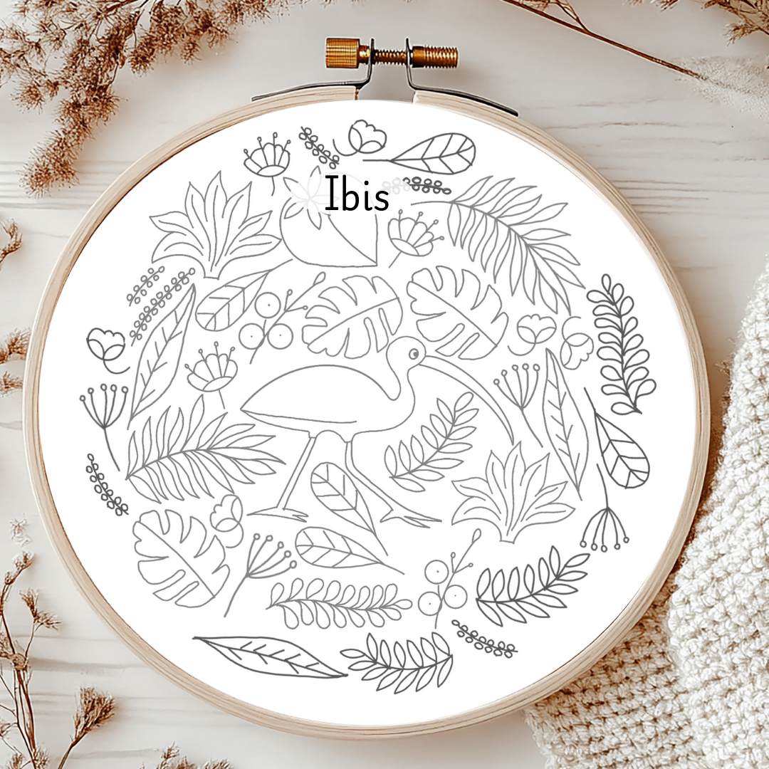 Embroidery hoop with a black and white floral and bird design on a light wooden surface.