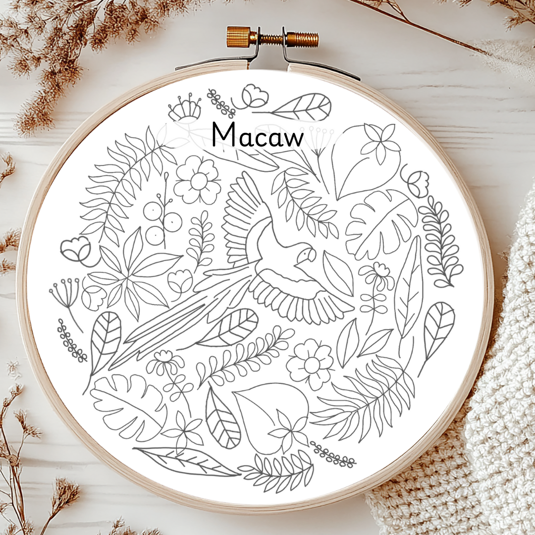 Embroidery hoop with a line drawing of a macaw and foliage on a white background.