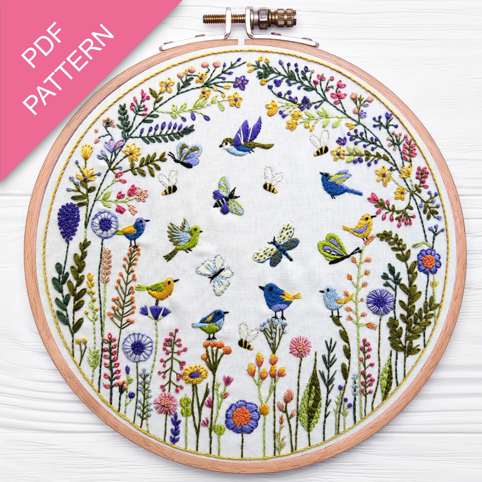 Embroidery hoop with floral and bird design on a white background