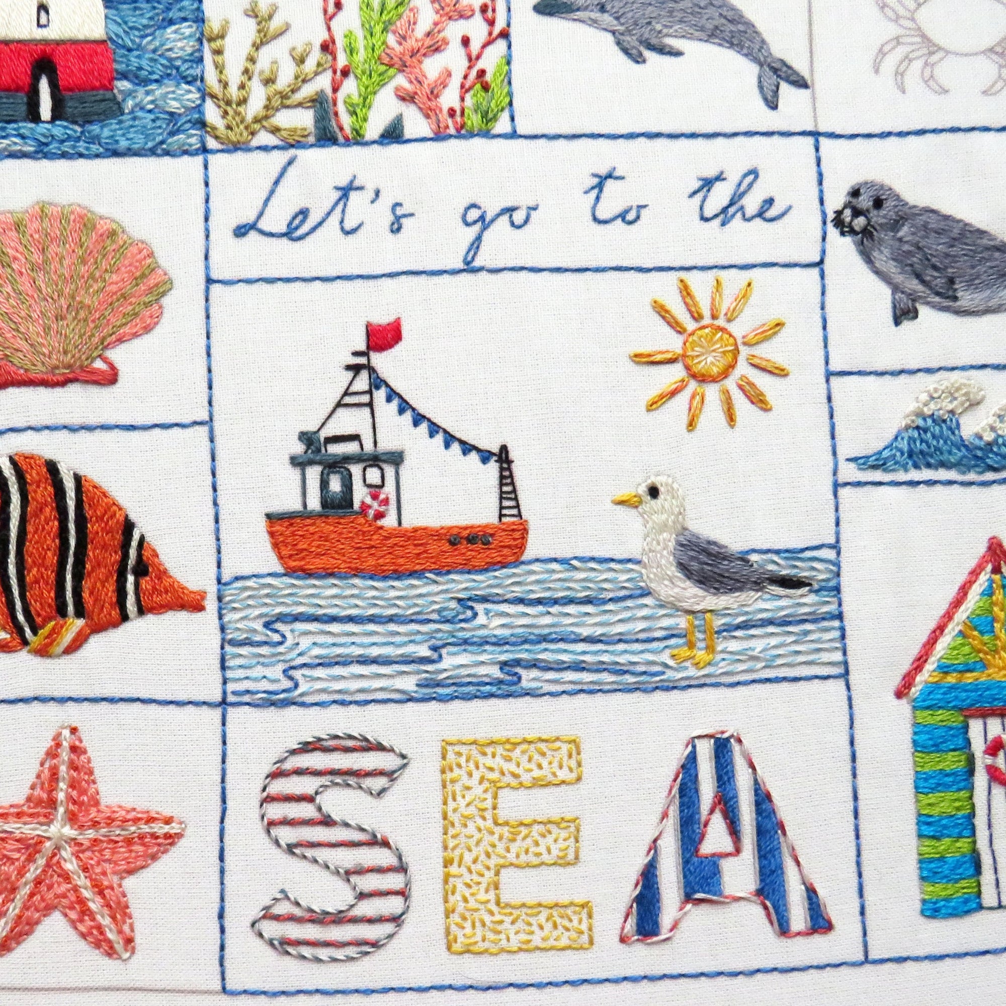Embroidered fabric with sea-themed designs including a boat, fish, and 'Let's go to the Sea' text.