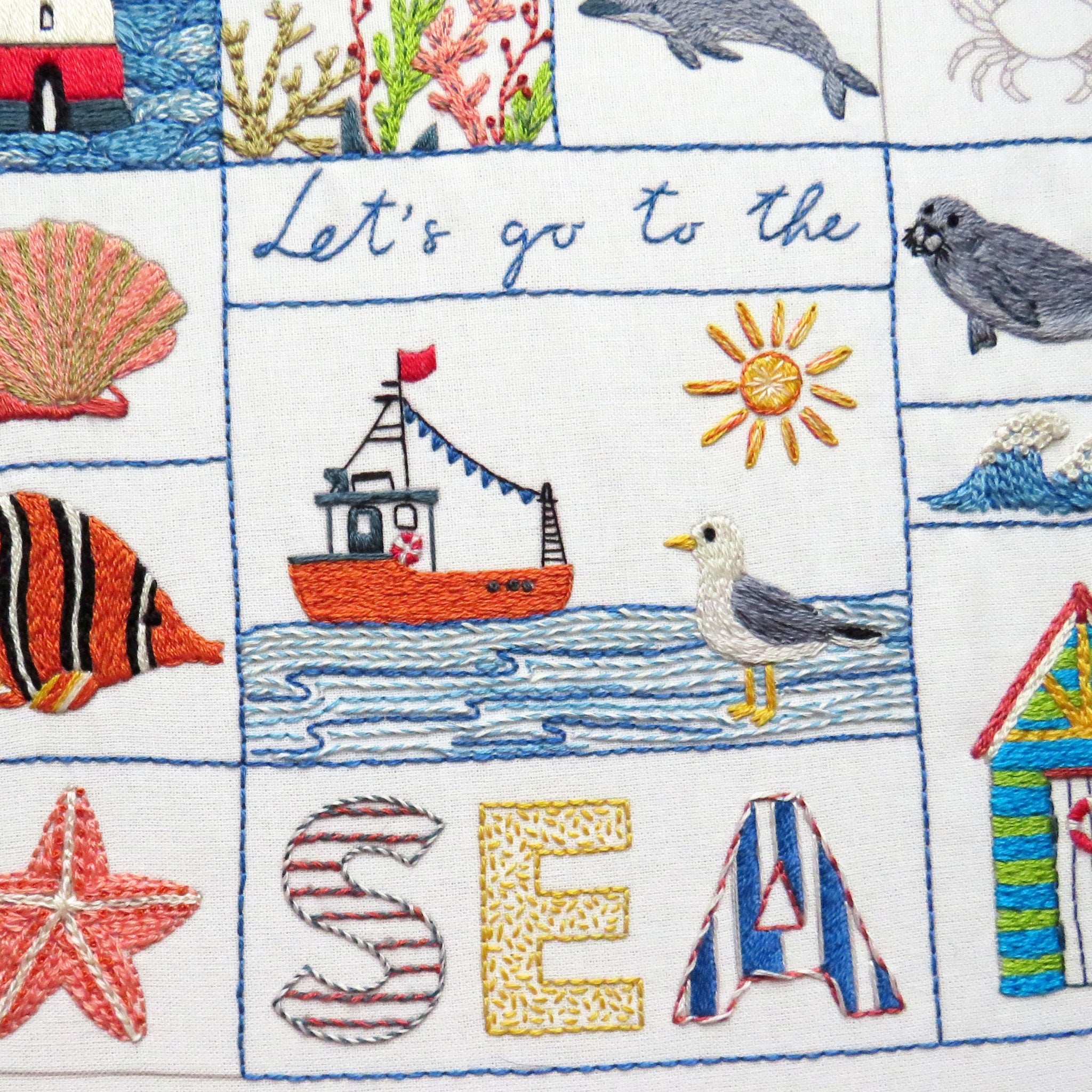 Embroidered fabric with sea-themed designs including a boat, fish, and 'Let's go to the Sea' text.