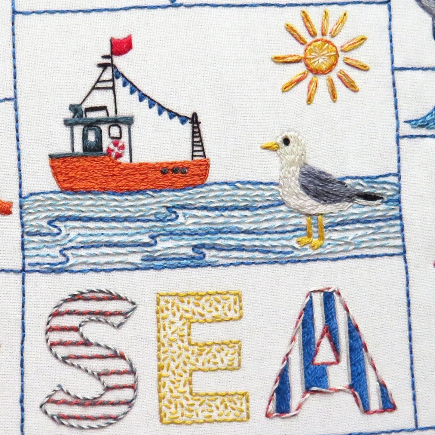 Embroidered design with a boat, seagull, and text 'Let's go to the Sea' on a white background.