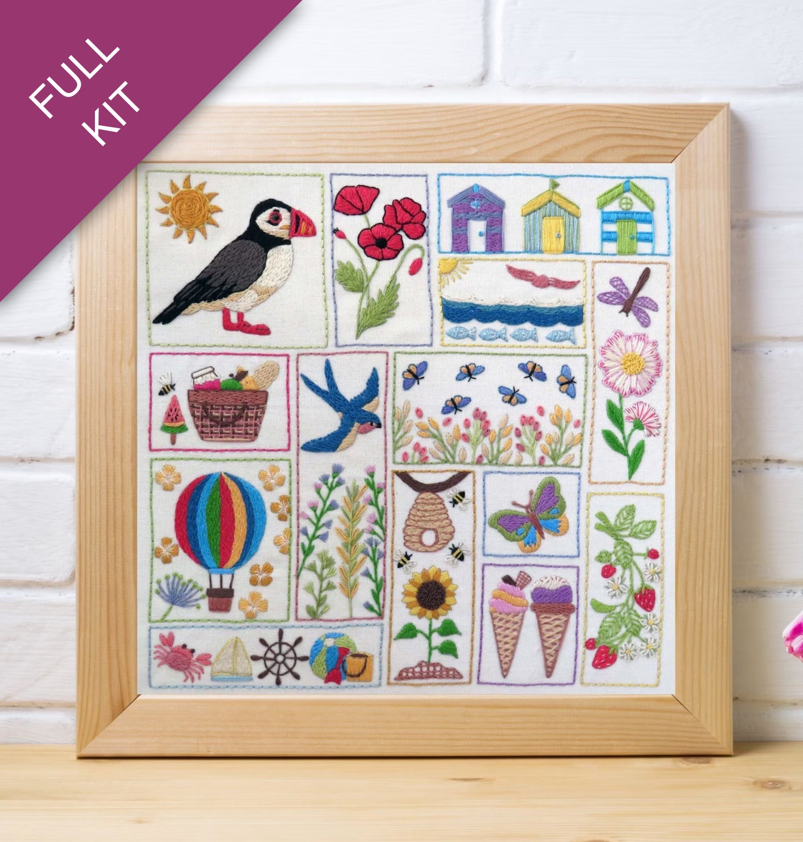 Framed embroidered sampler with various designs including a puffin, flowers, and animals on a white background.
