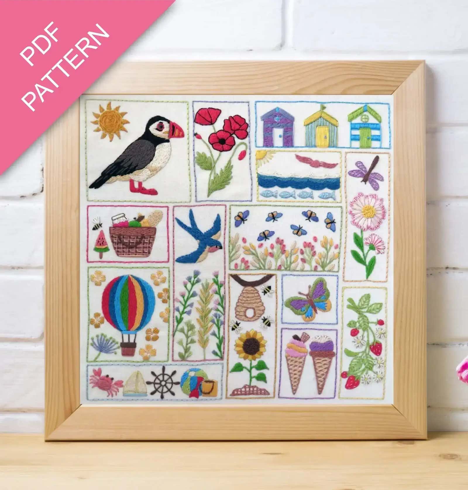 Framed embroidered sampler with various designs including a puffin, flowers, and animals on a white background.