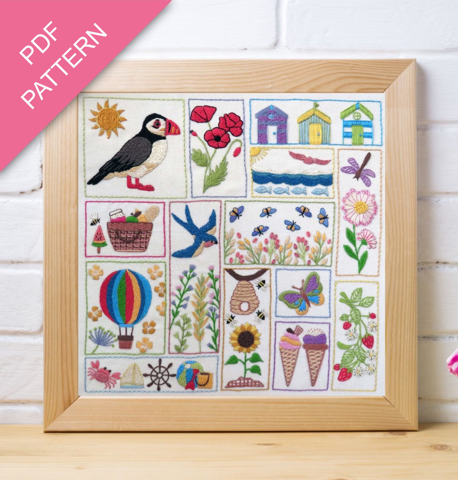 Framed embroidered sampler with various designs including a puffin, flowers, and animals on a white background.