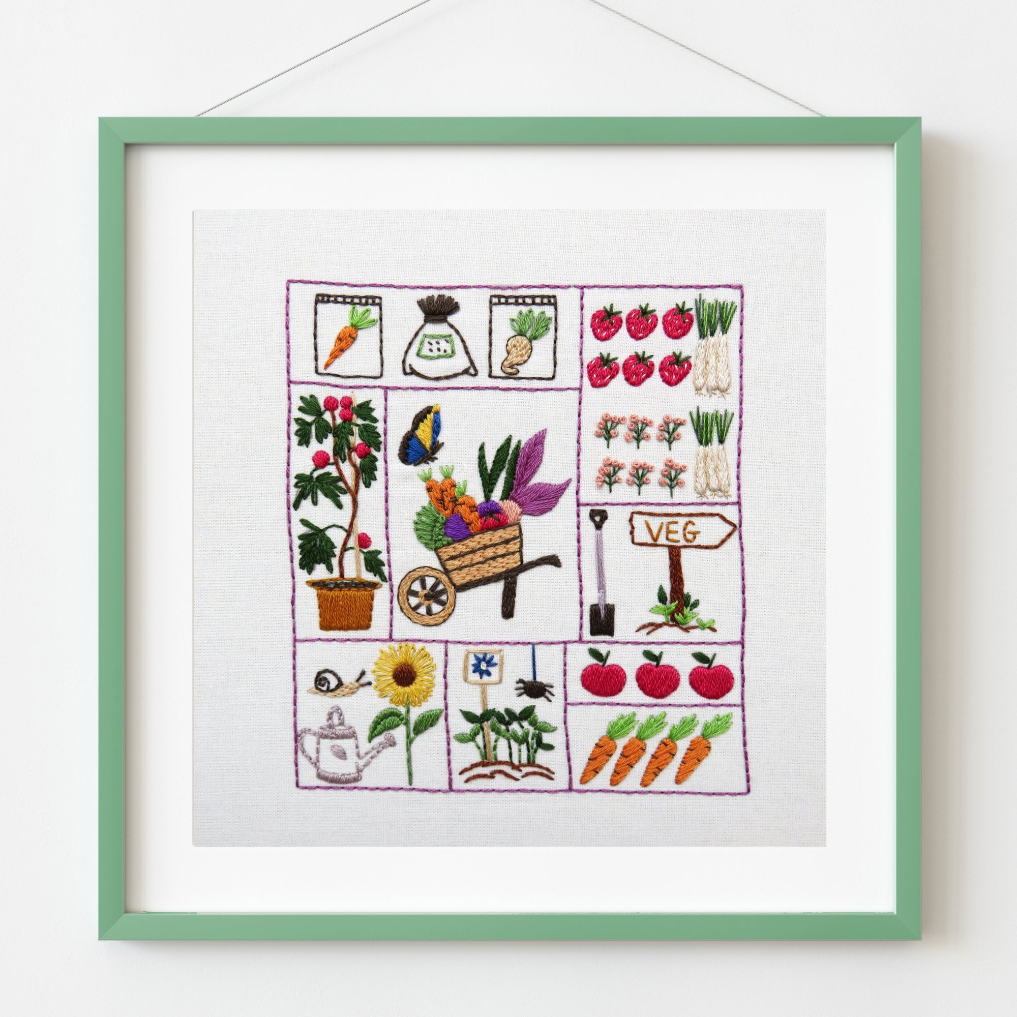 Framed embroidery with gardening-themed designs on a white background