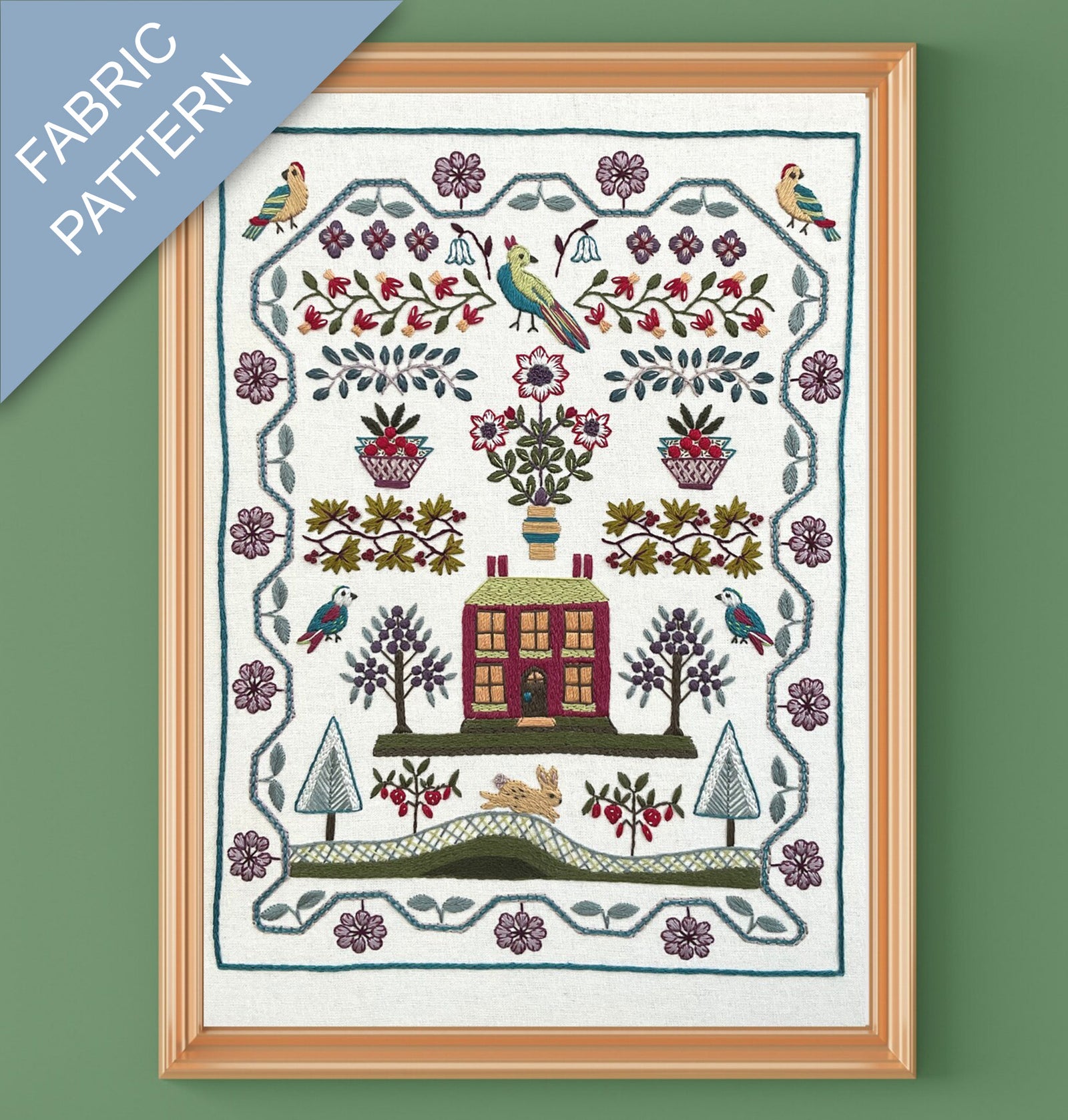 Framed fabric pattern with a house, trees, and birds design on a green background