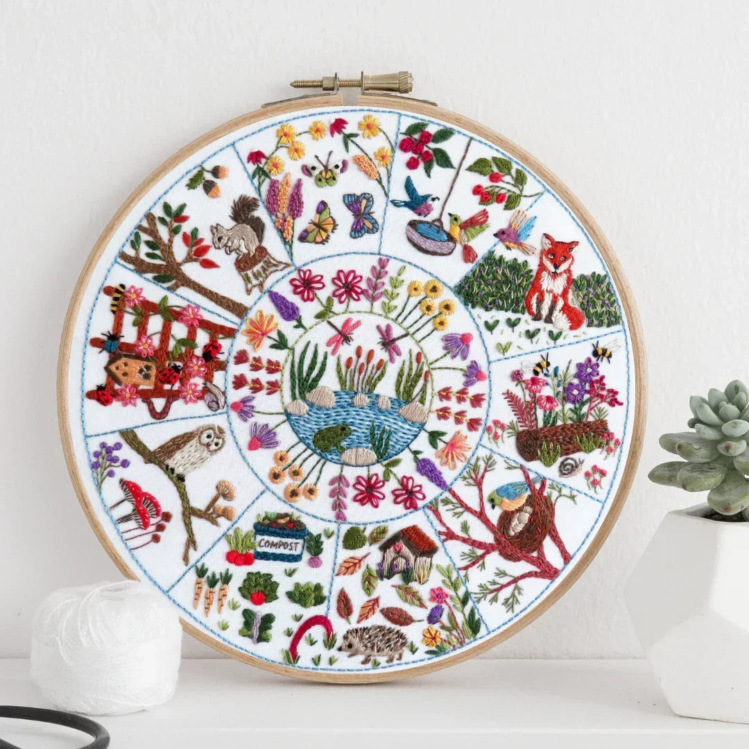 Embroidery hoop with a colorful floral and nature-themed design on a white background