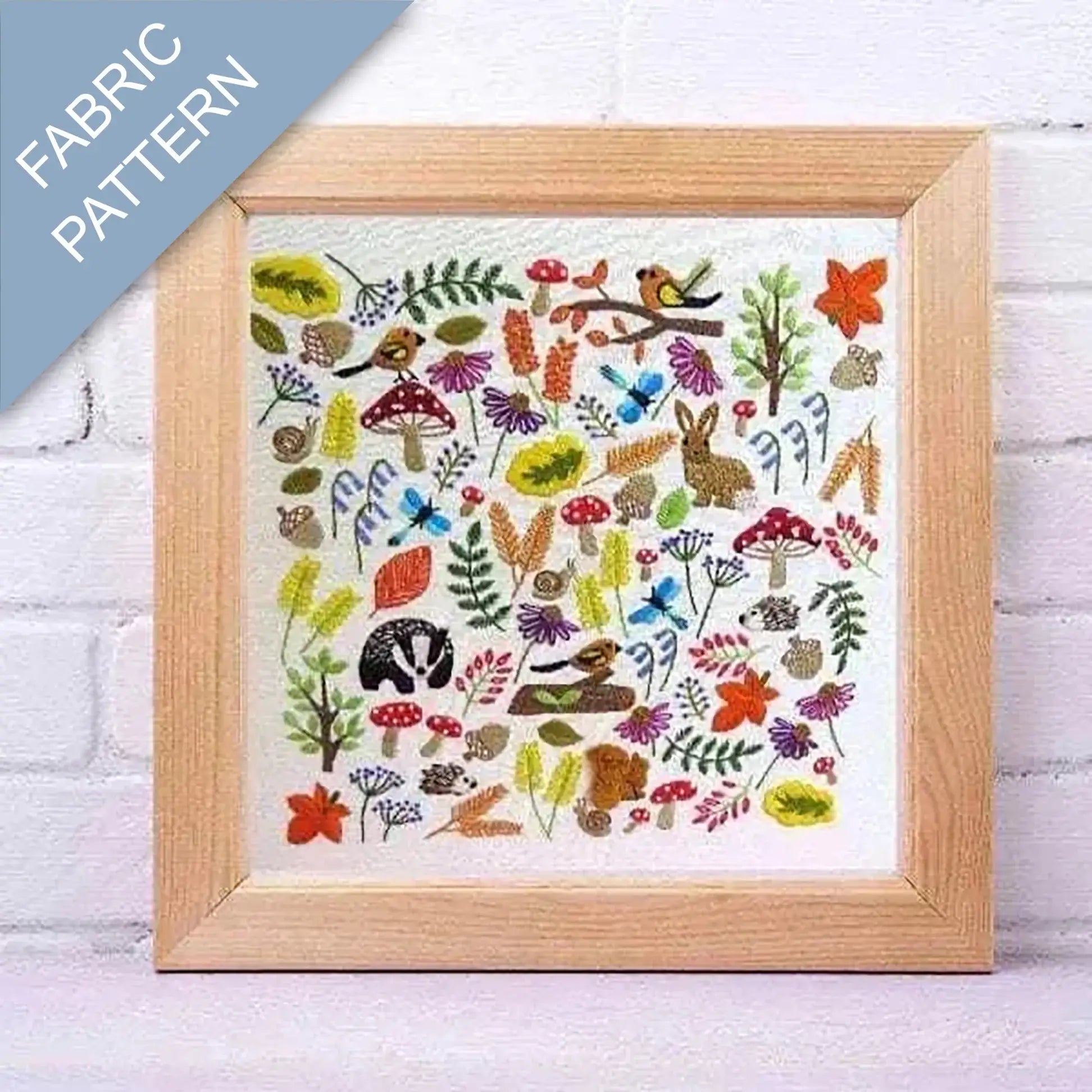 Framed fabric pattern with nature-themed design on a white brick wall background