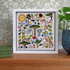 Framed artwork with colorful animals and nature elements on a wooden surface.