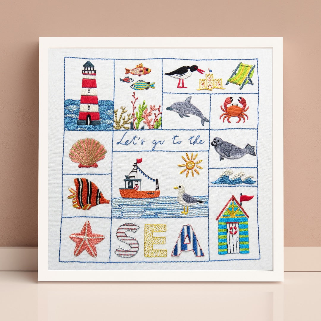 Framed cross-stitch art with sea-themed designs on a beige background