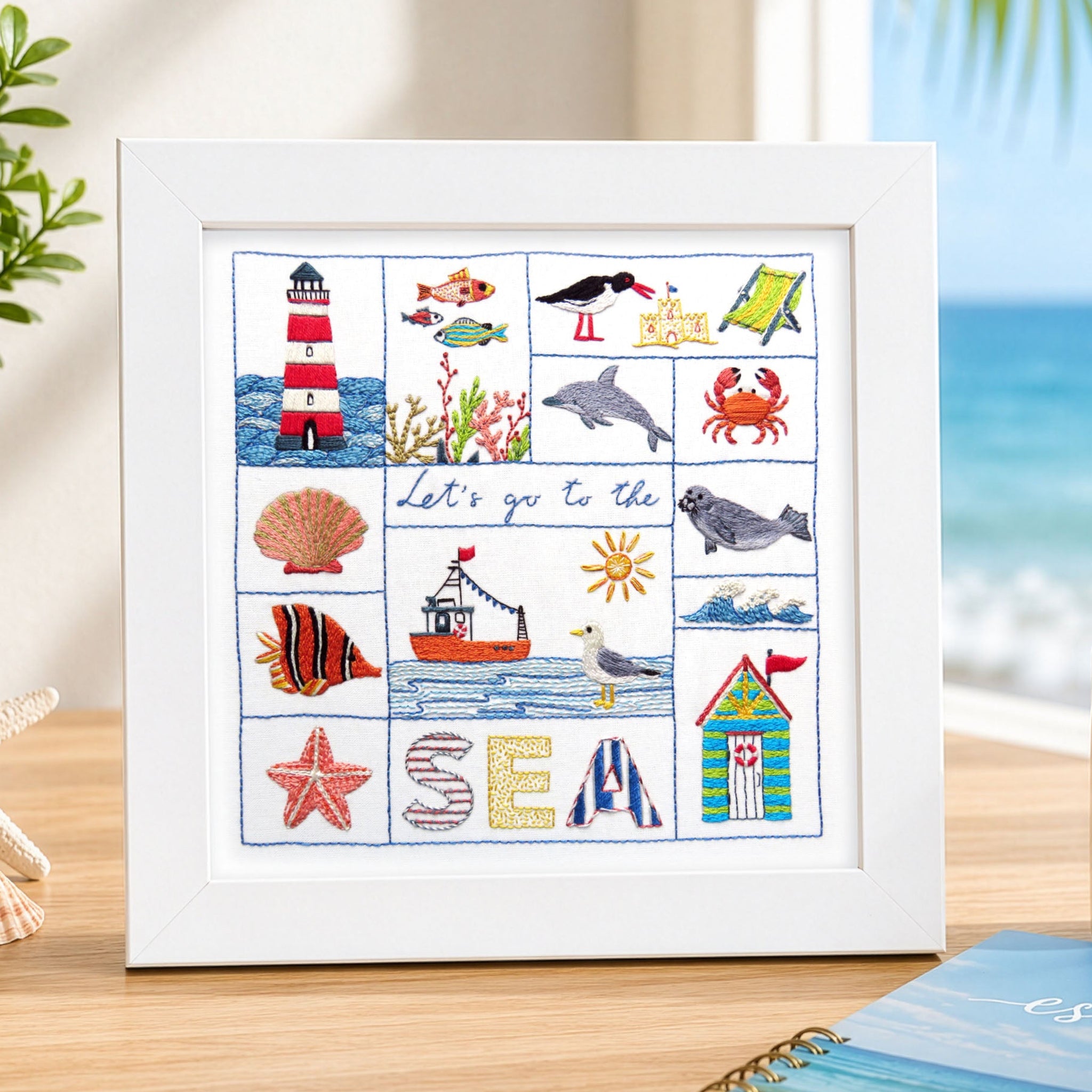 Framed beach-themed artwork on a desk with a mug and notebook in the background.
