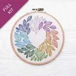 Embroidery hoop with colorful leaf patterns on a white background