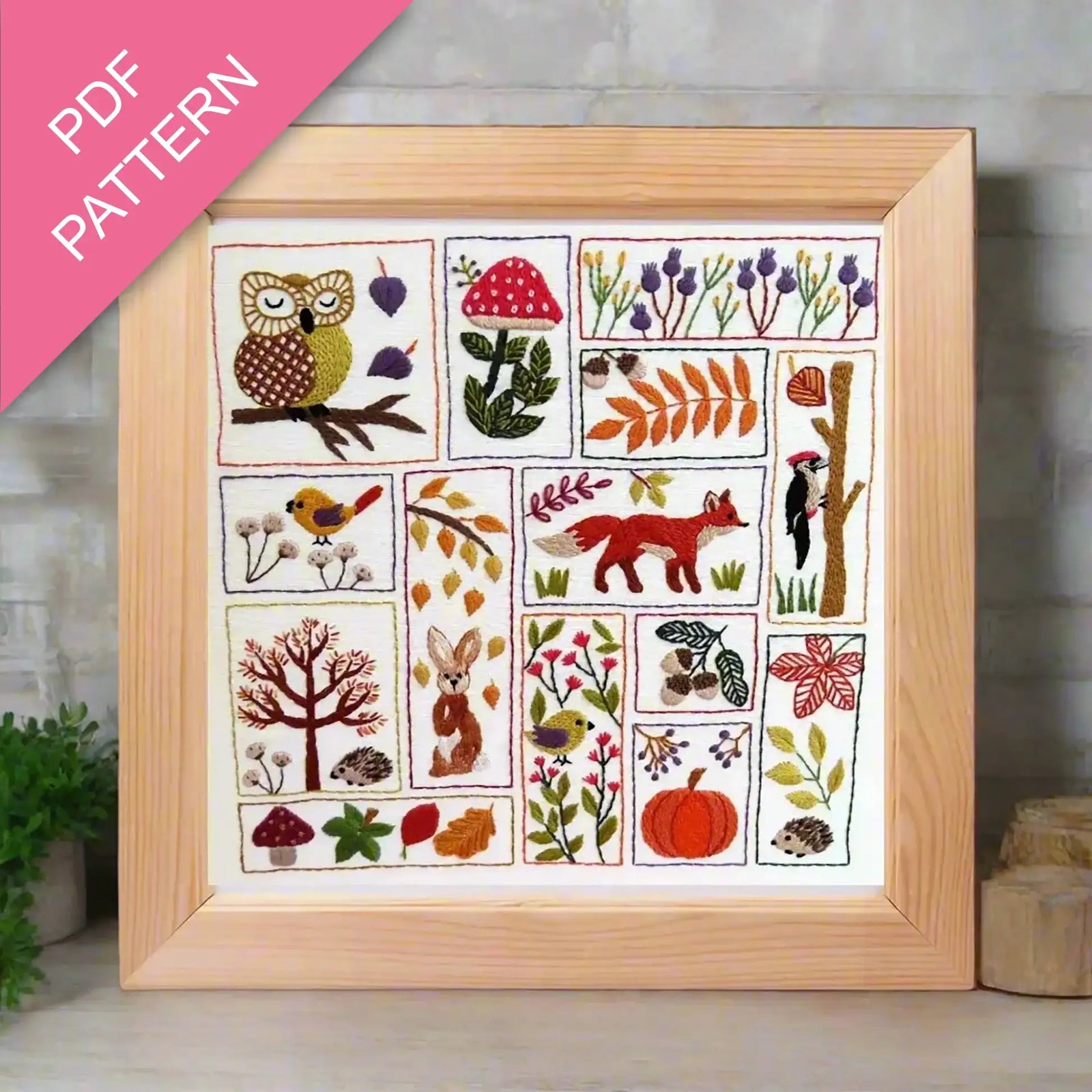 Framed embroidery pattern with nature-themed designs on a wooden surface.