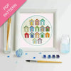Embroidery kit with colorful beach hut design, thread, and tools on a white background.