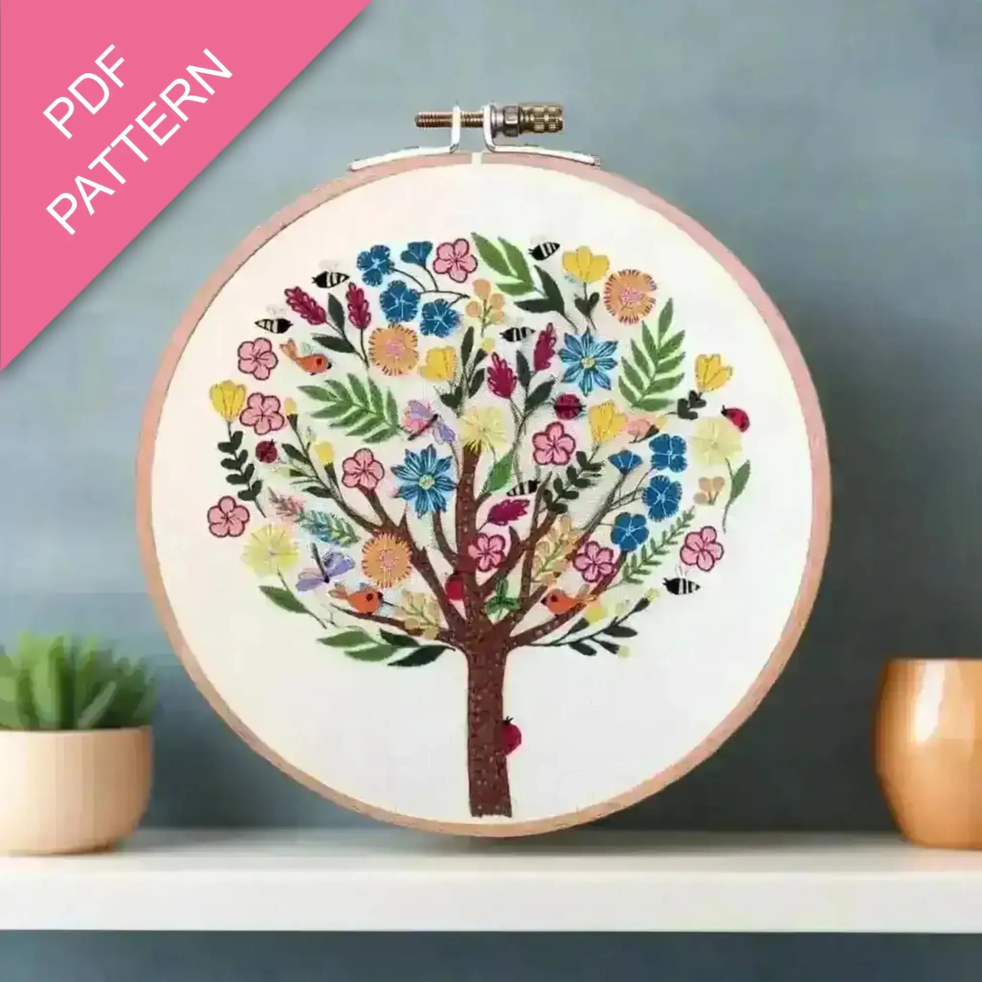 Embroidery hoop with a colorful tree design on a gray background