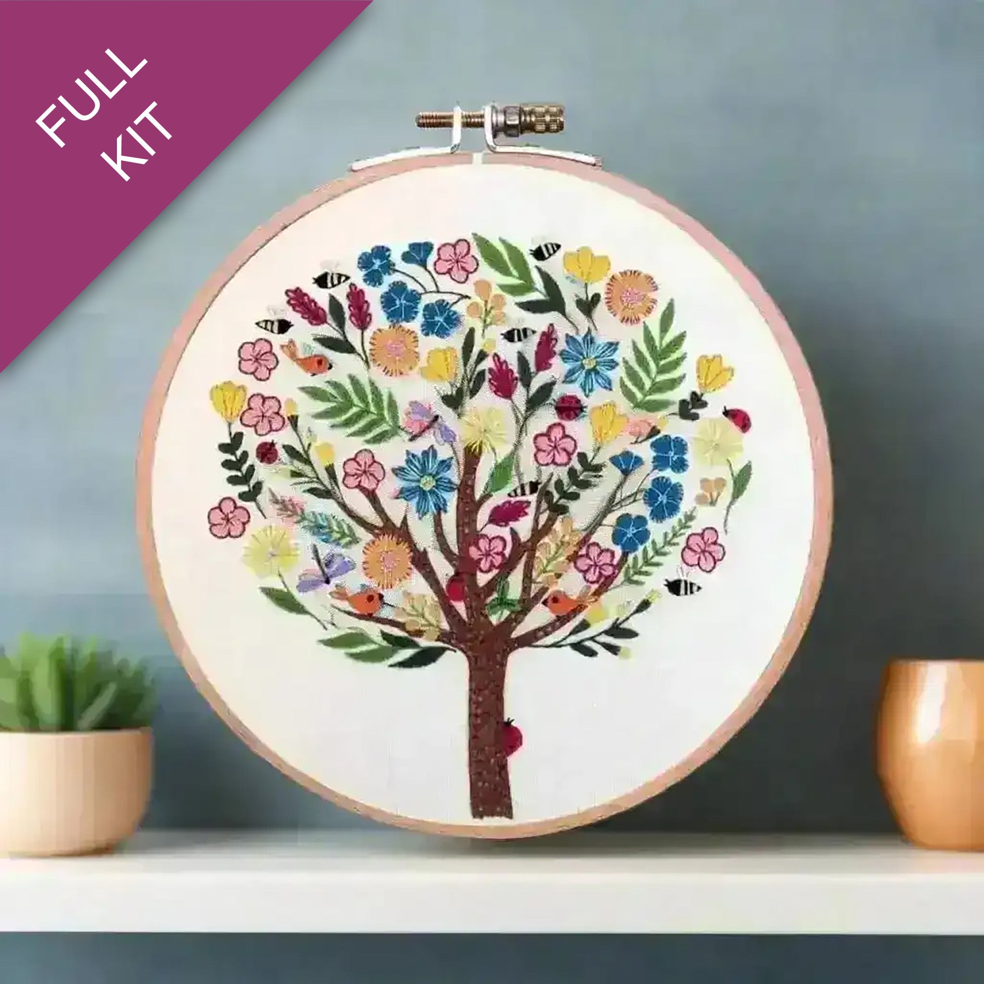 Embroidery hoop with a colorful tree design on a white background