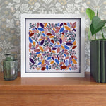 Framed artwork with colorful leaf pattern on a wooden surface with decorative background