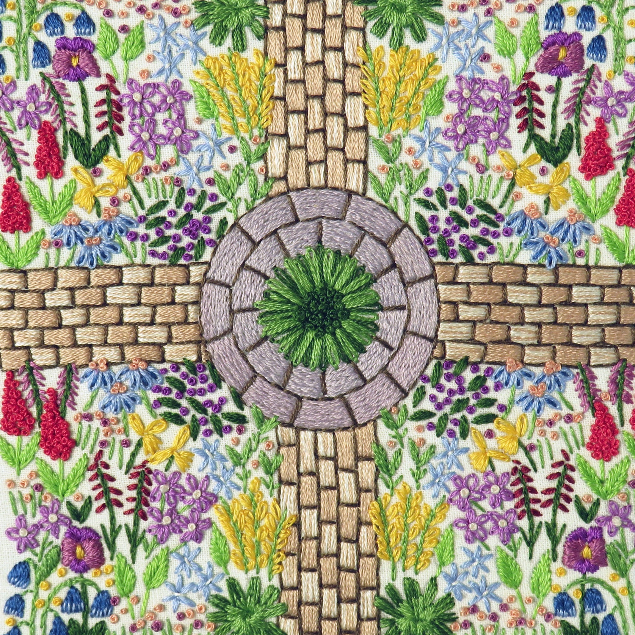 Embroidered design of a garden with flowers and a stone path.