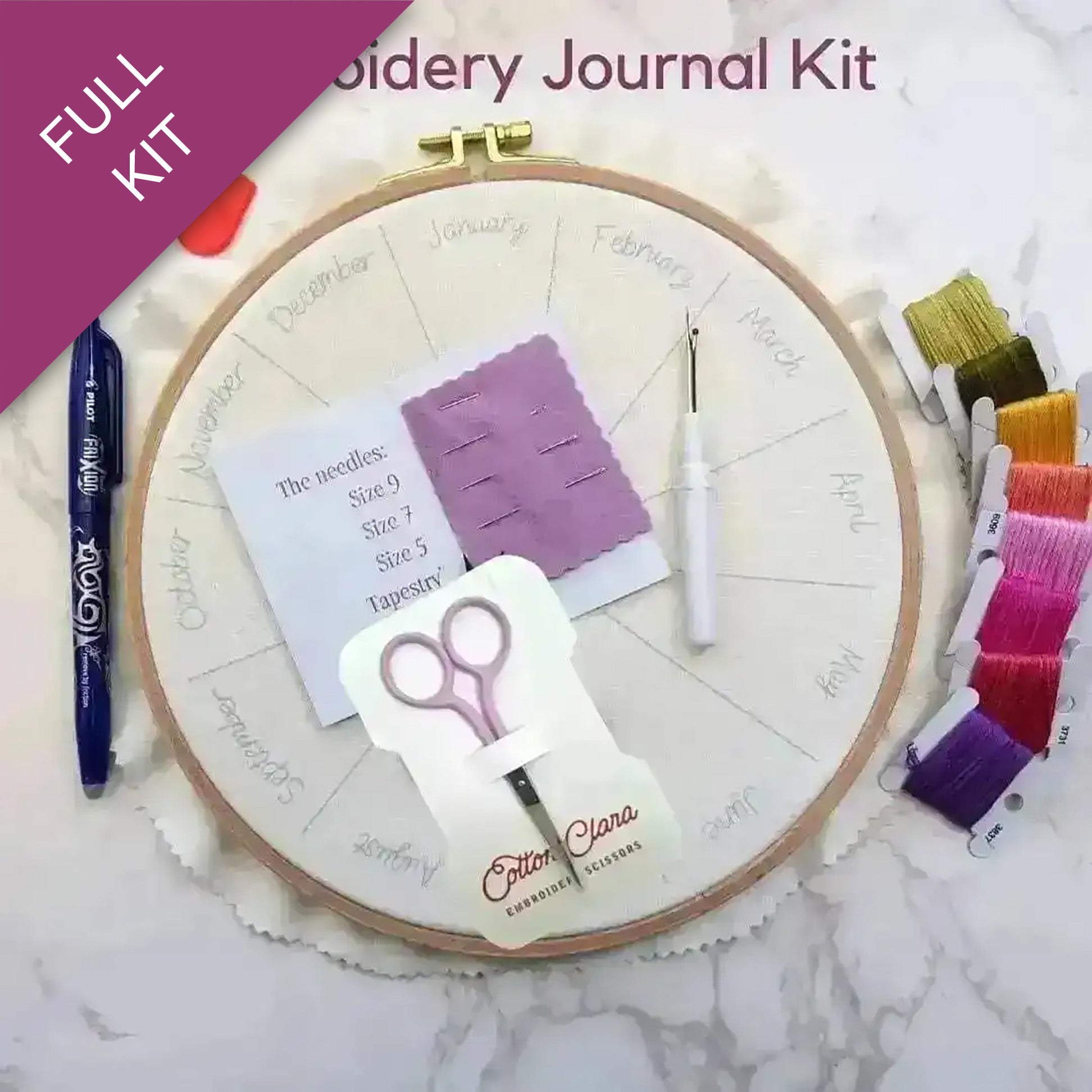 Embroidery kit with hoop, threads, scissors, and other supplies on a marble surface.