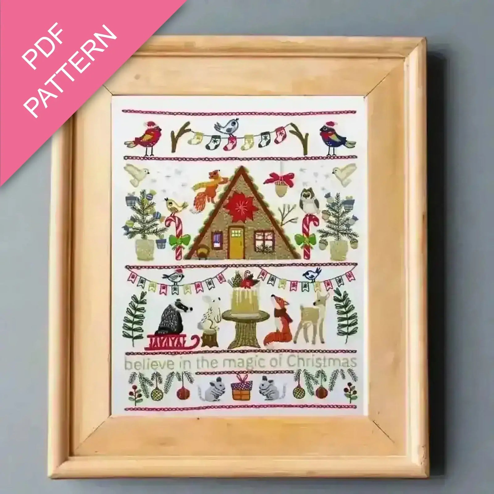 Framed cross-stitch pattern with Christmas-themed design on a gray background