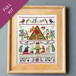 Framed cross-stitch kit with Christmas-themed design on a gray background