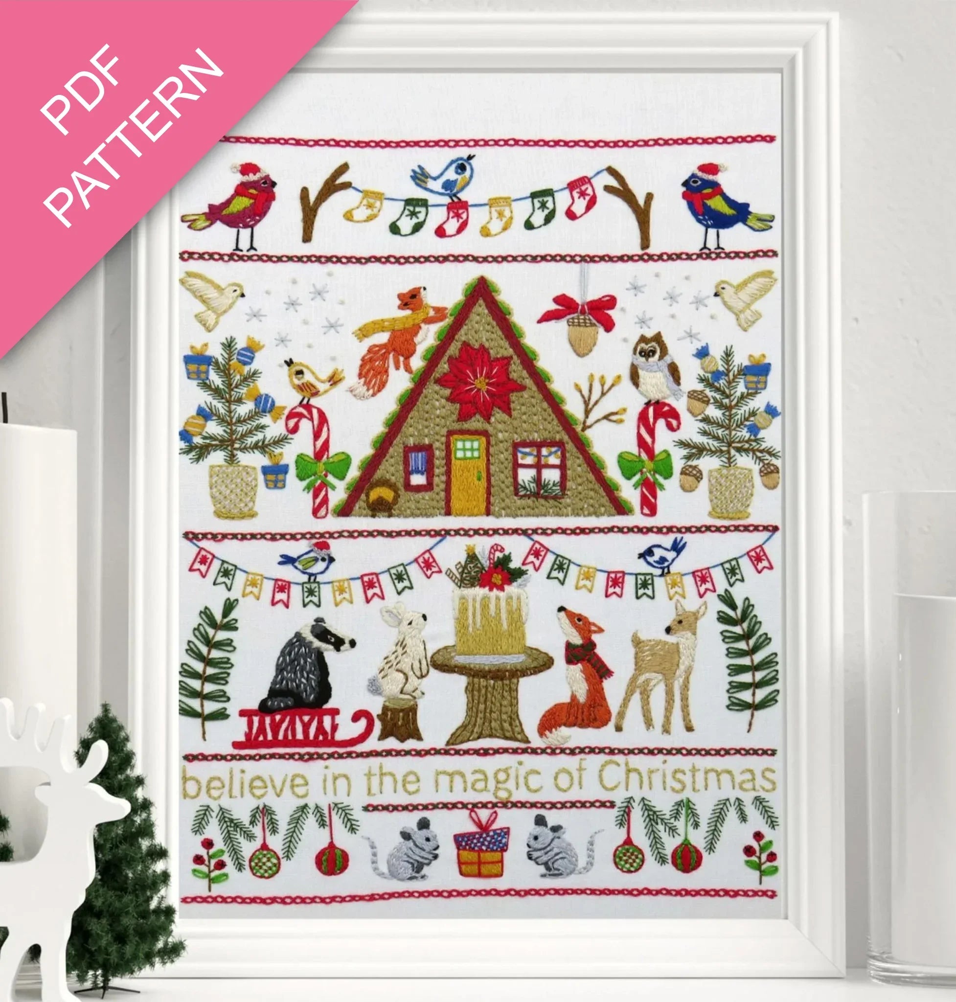 Christmas-themed cross-stitch pattern with a cabin, animals, and festive elements on a white background.