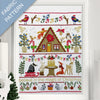 Framed fabric pattern with Christmas-themed design featuring a cabin, animals, and festive elements.