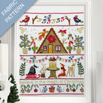 Framed fabric pattern with Christmas-themed design featuring a cabin, animals, and festive elements.