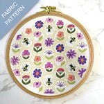 Embroidery hoop with floral and bee pattern on a marble surface