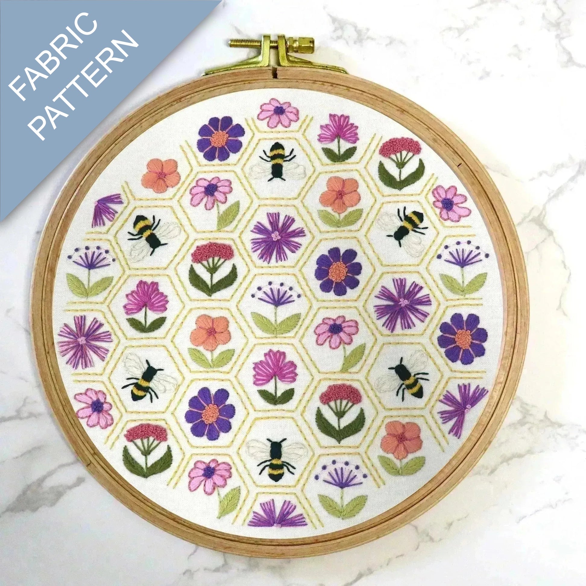 Embroidery hoop with floral and bee pattern on a marble surface