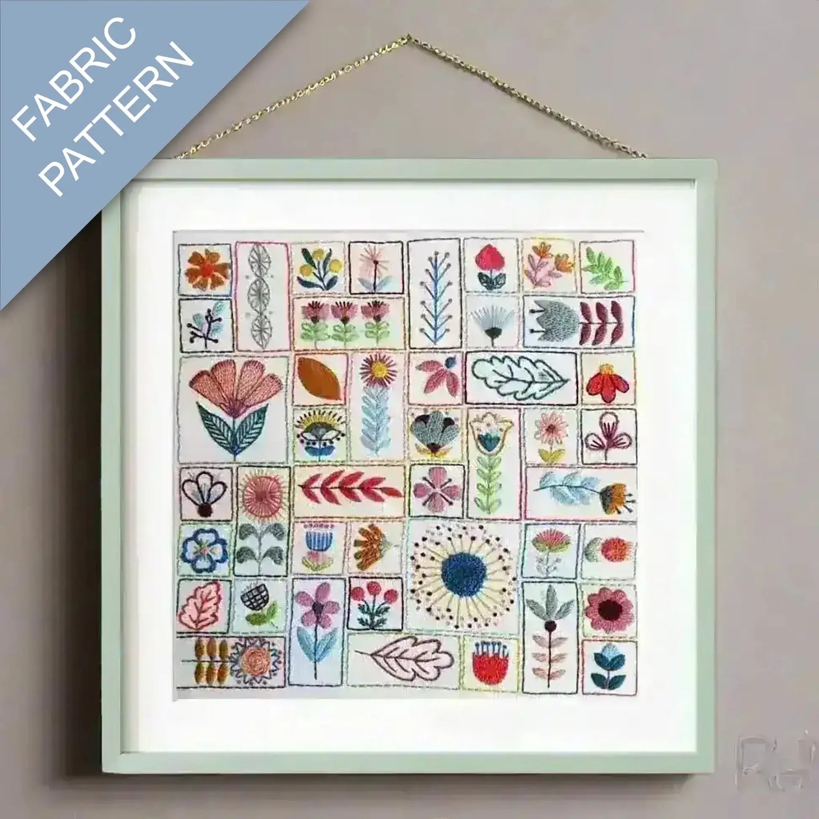 Framed fabric pattern with various floral designs on a plain wall.