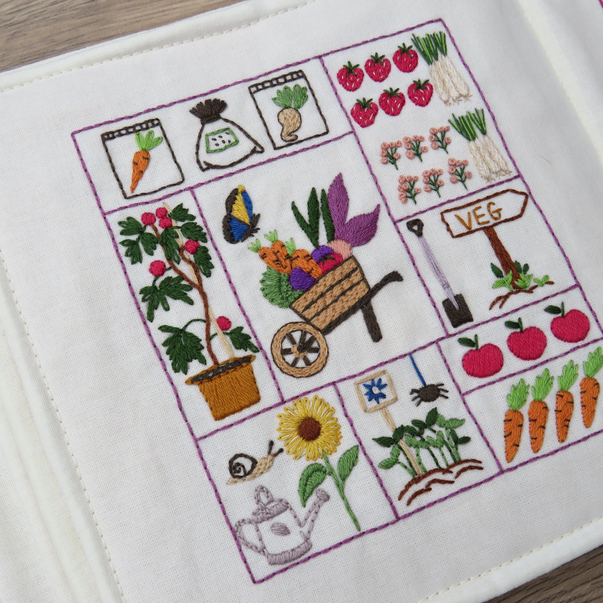 Embroidered panel with gardening-themed designs on a white background