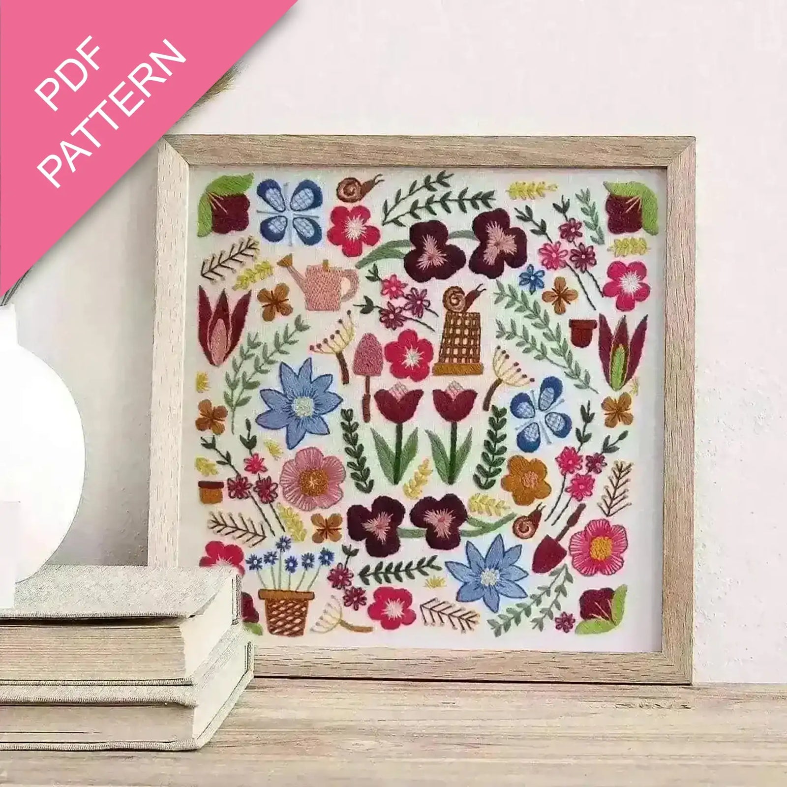 Embroidery pattern with colorful flowers and plants in a wooden frame on a white surface.