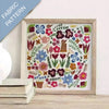 Framed fabric pattern with colorful floral and gardening-themed design on a white background.